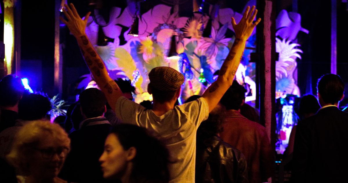 A member of the audience raises his arms in front of the stage at La Brasserie communale
