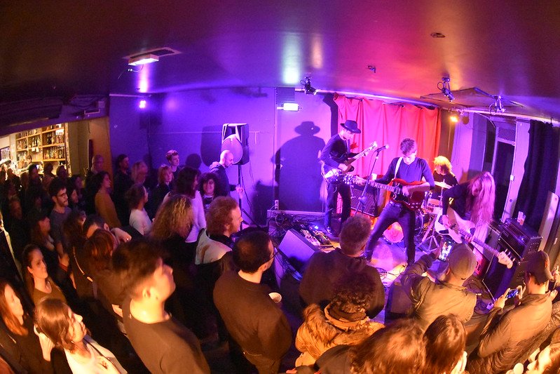 Un groupe joue devant une salle comble à L'Intermédiaire, sous des lumières violettes